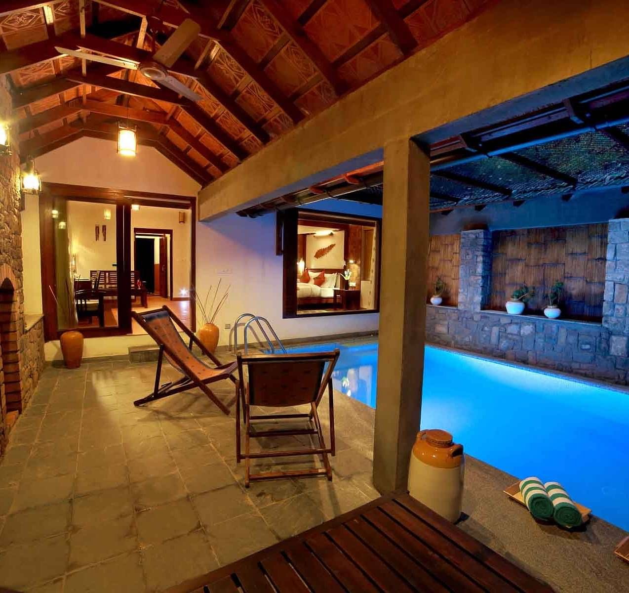 A pool and poolside area with loungers | Vythiri Resort. Wayanad